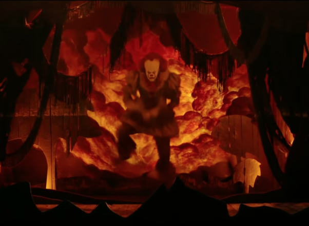 A still from the 2017 film IT showing Pennywise the clown dancing in the dead lights
